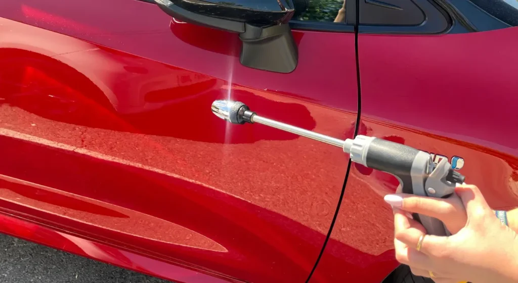 Jetterix limpiando un coche rojo con manguera de jardín